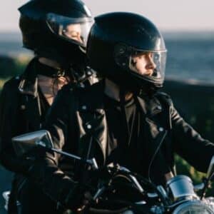 couple of bikers in helmets riding classical motorcycle on country road